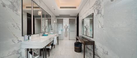 A modern bathroom with marble walls, a large mirror, a round sink, and a vanity with a towel rack.