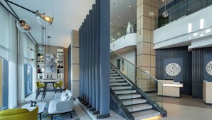 Un interior moderno con una escalera, una zona de estar y un mostrador de recepción.