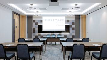 A conference room with a large screen displaying 'COURTYARD BY MARRIOTT Chisinau'.