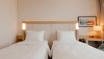 Ein Hotelzimmer mit zwei Betten, einem Nachttisch mit Lampe, einem Bild an der Wand und einem Telefon auf dem Tisch.