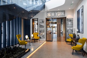 A modern lobby with a 'NEW YORK' sign, seating area, and a staircase. - Courtyard by Marriott Chisinau (Chisinau)