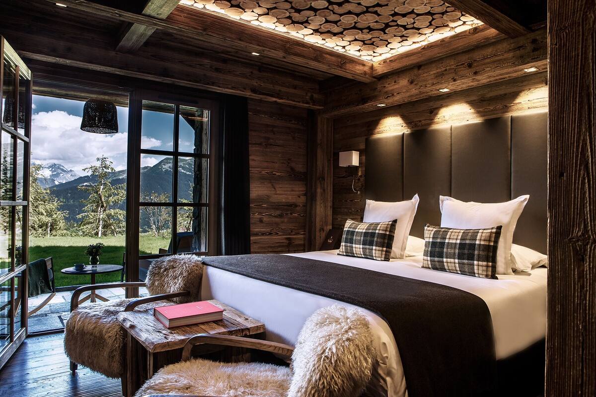 Een gezellige slaapkamer met een groot bed, houten wanden en uitzicht op bergen.