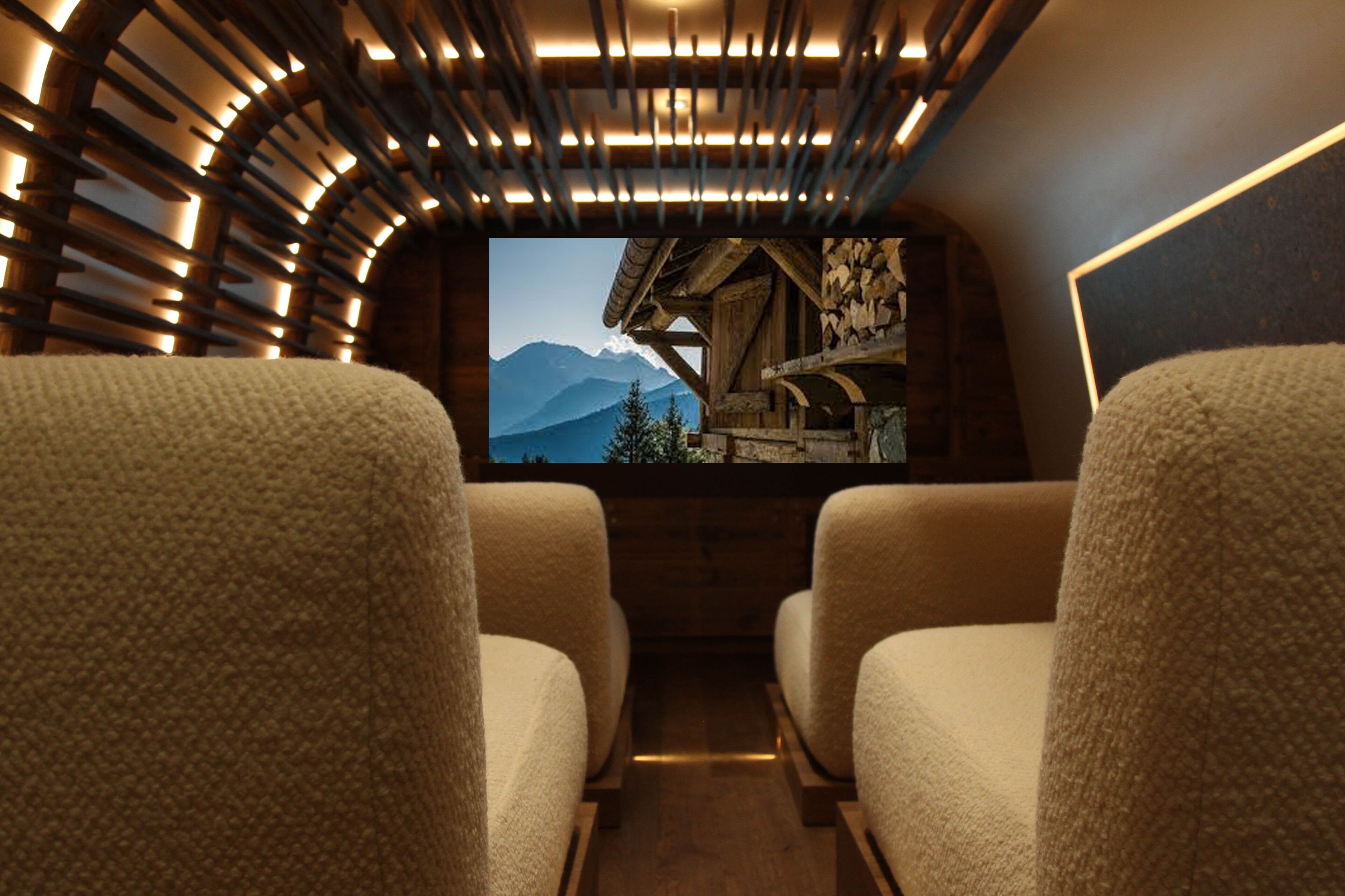 A cozy interior with two plush chairs facing a television screen displaying a mountainous landscape.
