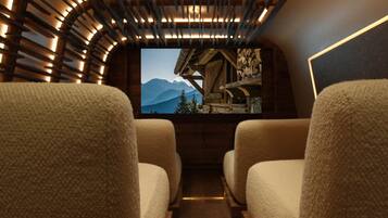 A cozy interior with two plush chairs facing a television screen displaying a mountainous landscape.