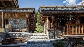 Un bâtiment rustique en bois, avec des murs en pierre, une terrasse en bois et un bain à remous en pierre.