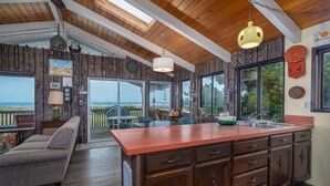 A spacious kitchen with wooden cabinets, a large island, and a view of the ocean.