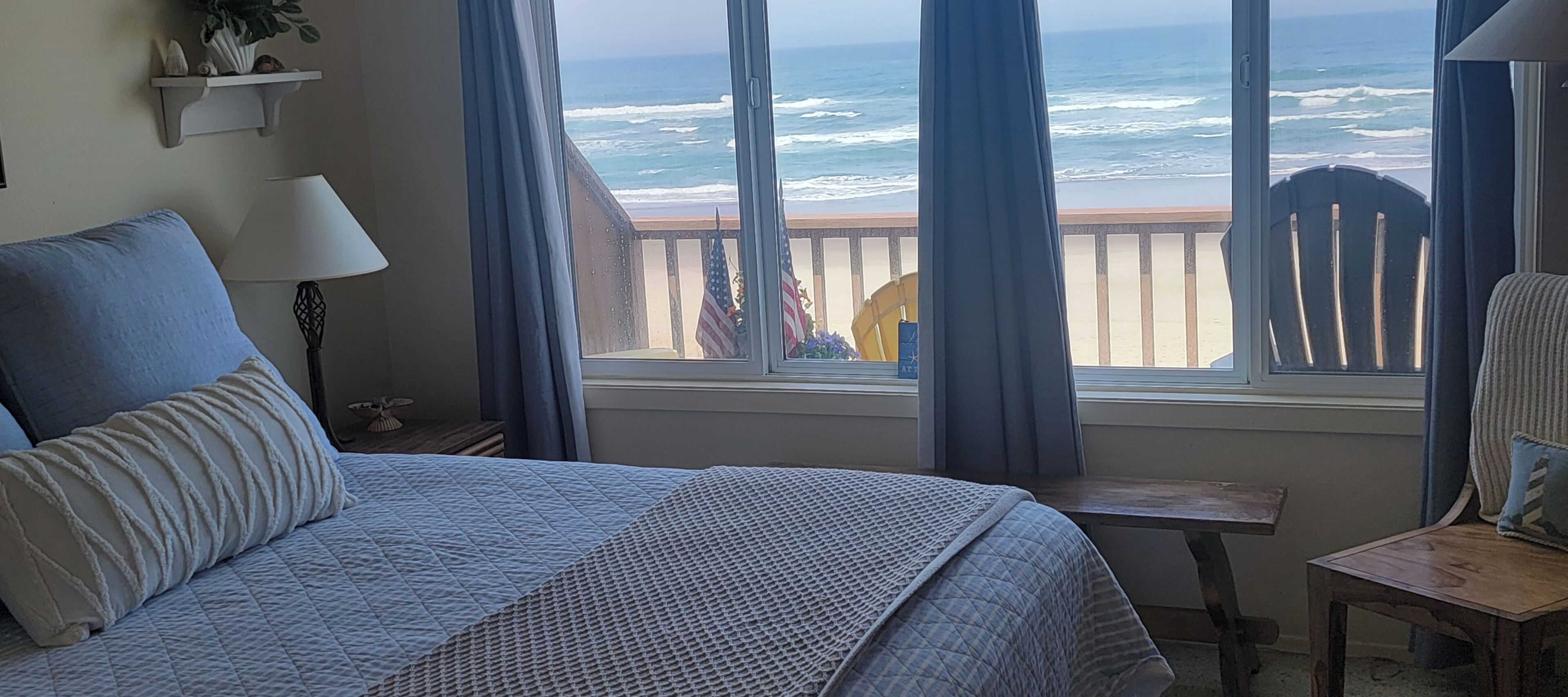 Une chambre à coucher avec un grand lit, une petite table, une chaise et une fenêtre donnant sur l’océan.