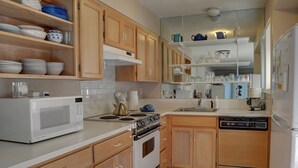 A kitchen with wooden cabinets, a white microwave, stove, and dishwasher.