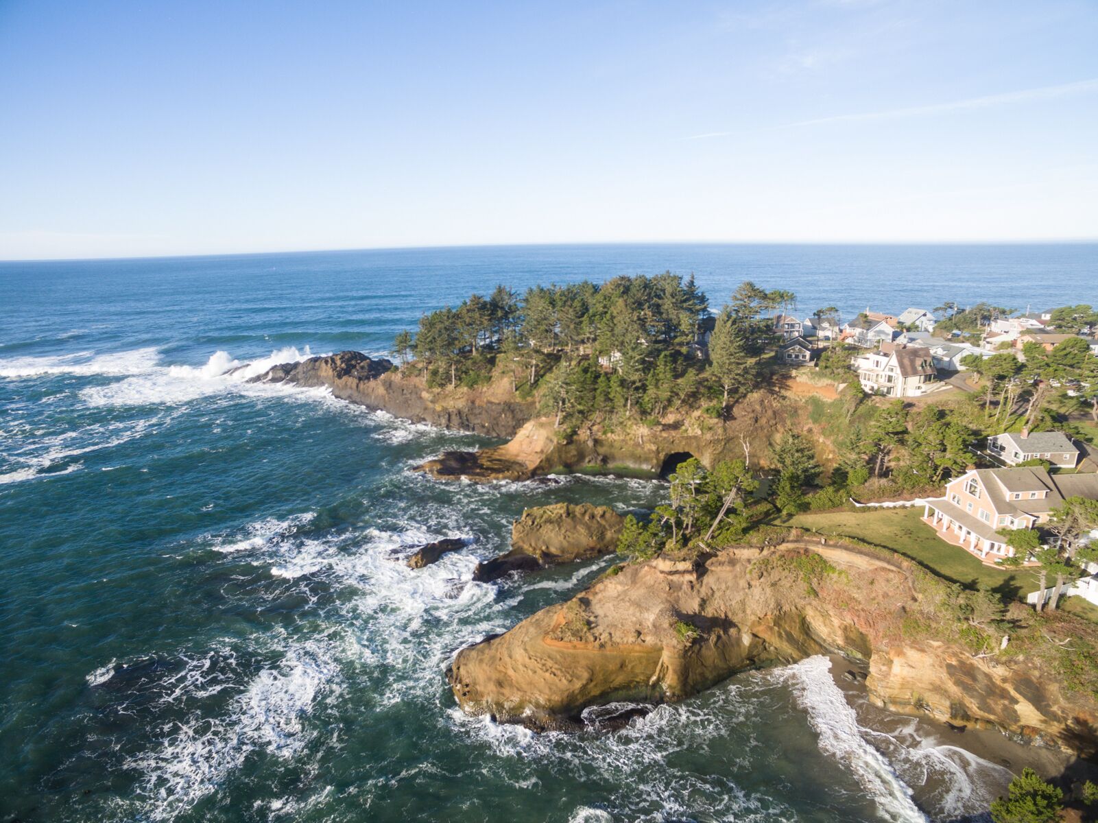 Une zone côtière caractérisée par des falaises rocheuses, des vagues de l’océan et des immeubles résidentiels.