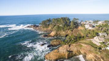 Une zone côtière caractérisée par des falaises rocheuses, des vagues de l’océan et des immeubles résidentiels.