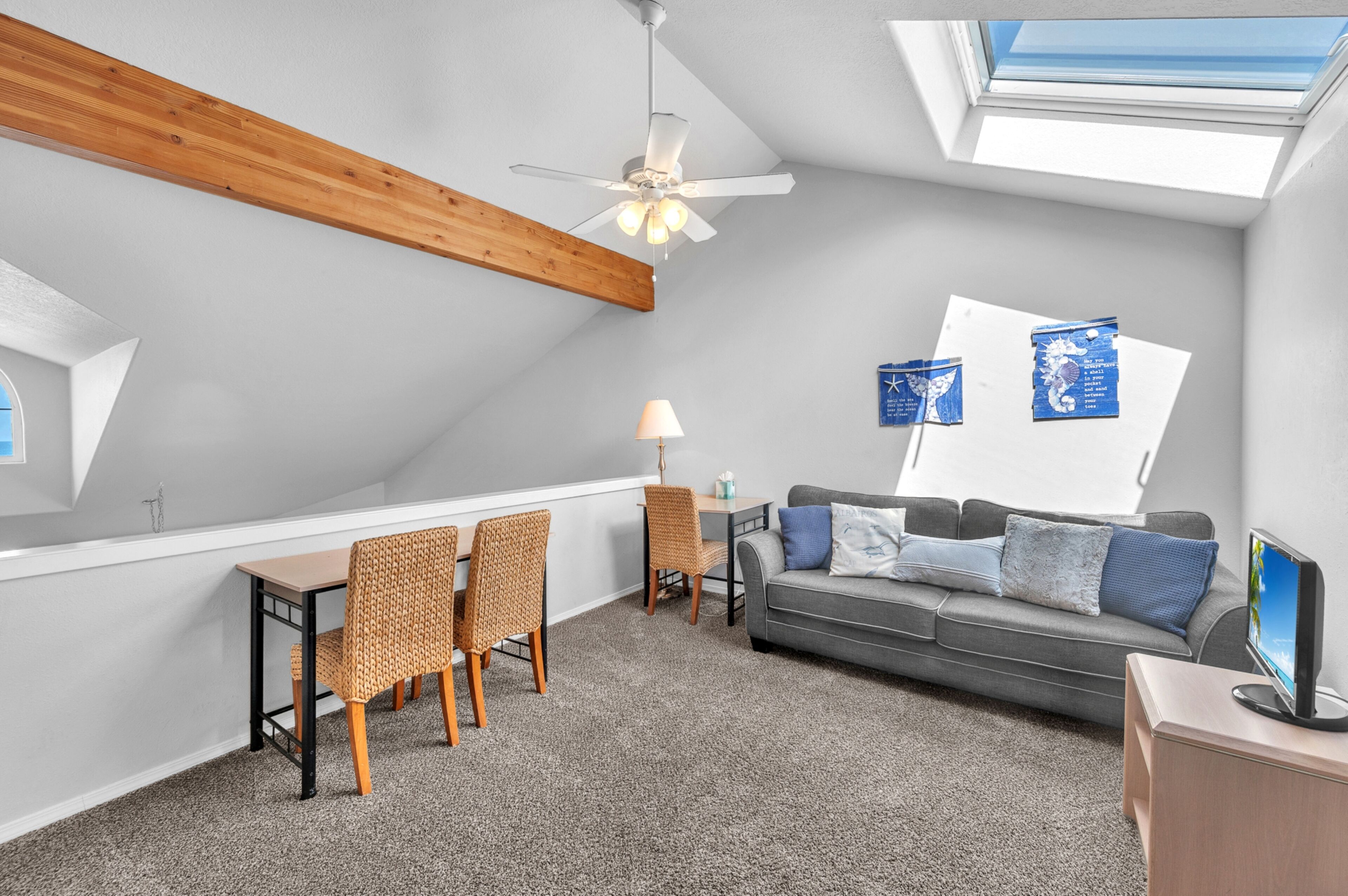 Una camera in stile loft con zona pranzo, divano, televisore e ventola a soffitto.