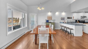 Una cocina moderna con armarios blancos, una mesa de comedor de madera y vistas al exterior.