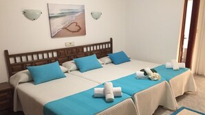 A double bed with two blue pillows and a white bedspread, a wooden headboard, and a painting of a beach scene on the wall. - Hotel Florida (Sanxenxo)