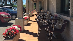 A covered outdoor seating area with stone columns, outdoor tables, and chairs. - Hotel Florida (Sanxenxo)
