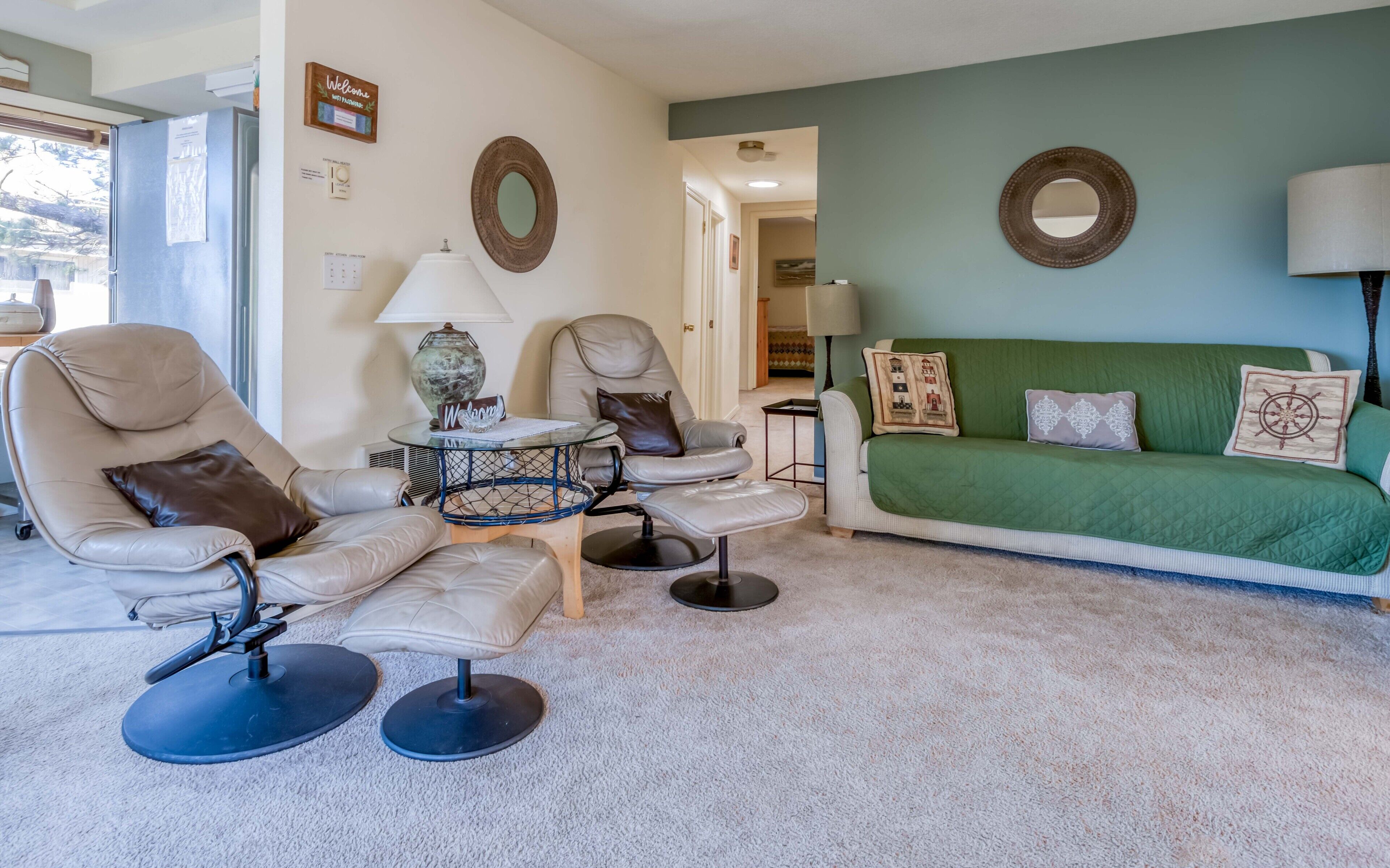 A living room with a green sofa, two armchairs, a coffee table, and a lamp.