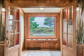 A wooden cabin with a large window, wooden walls, and a bench at the window's base. - Pet Friendly Beachfront Home, on the Promenade, Steps to the Sand, Close to Town (Seaside)