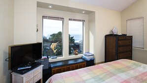 Une chambre à coucher comprenant un lit, une télévision, une commode et une fenêtre donnant sur l’extérieur.