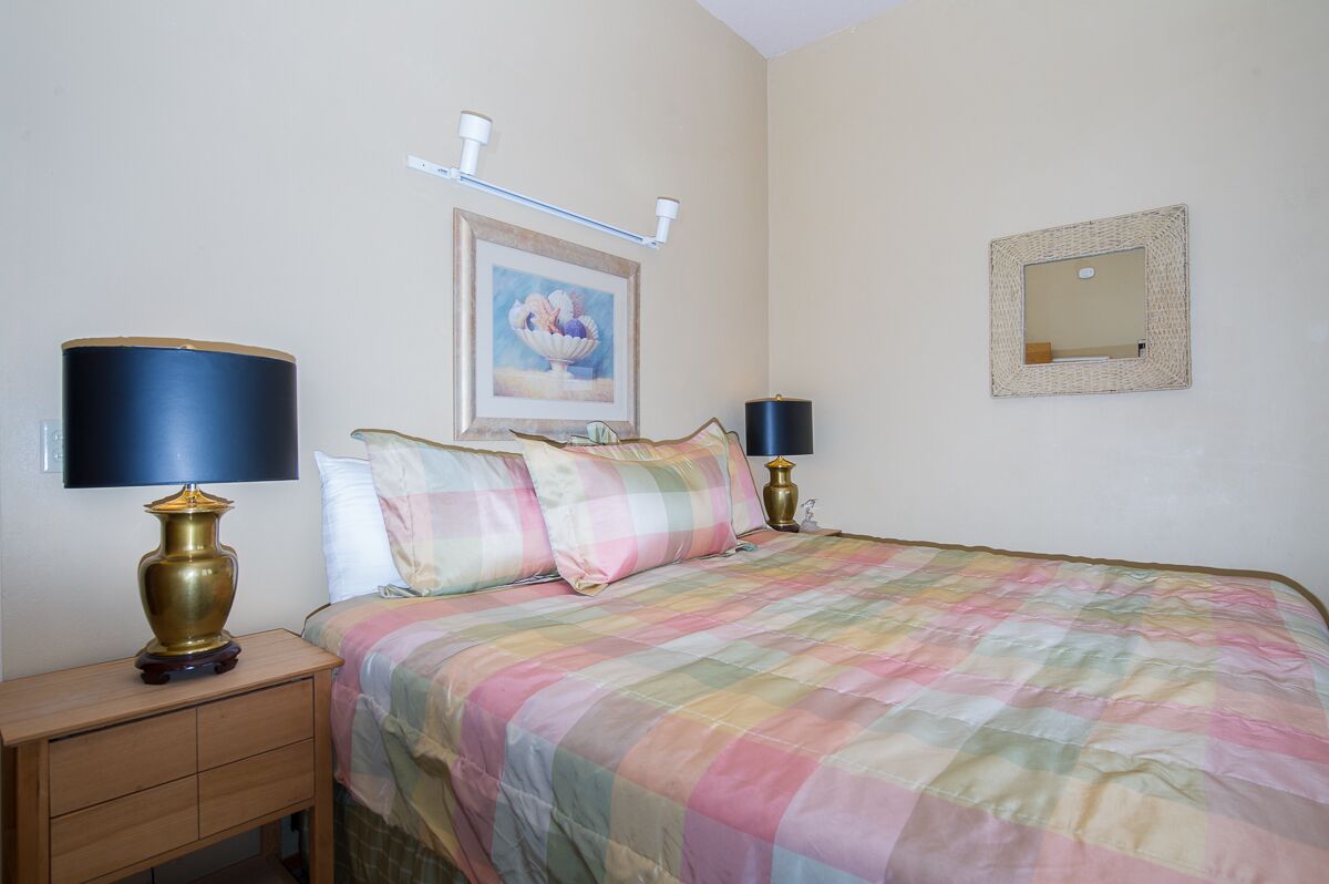 Un dormitorio con una cama, dos lámparas de noche, una mesita de noche, un cuadro enmarcado en la pared y un espejo.