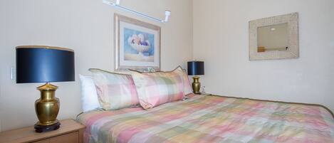 Un dormitorio con una cama, dos lámparas de noche, una mesita de noche, un cuadro enmarcado en la pared y un espejo.