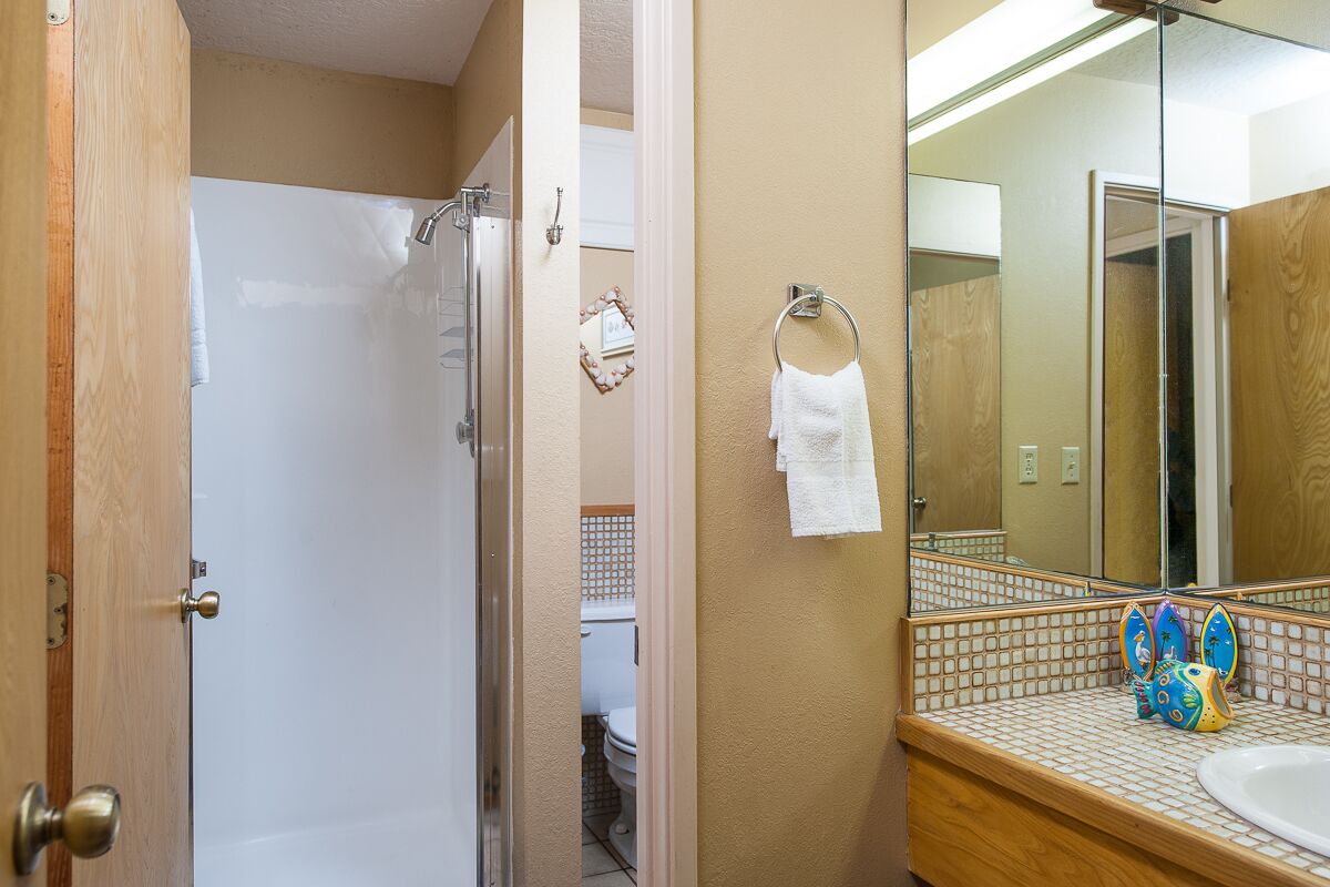 A bathroom with a shower, a sink, and a mirror.