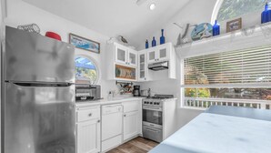 Une cuisine moderne avec des meubles blancs, un réfrigérateur en acier inoxydable et une cuisinière à gaz.