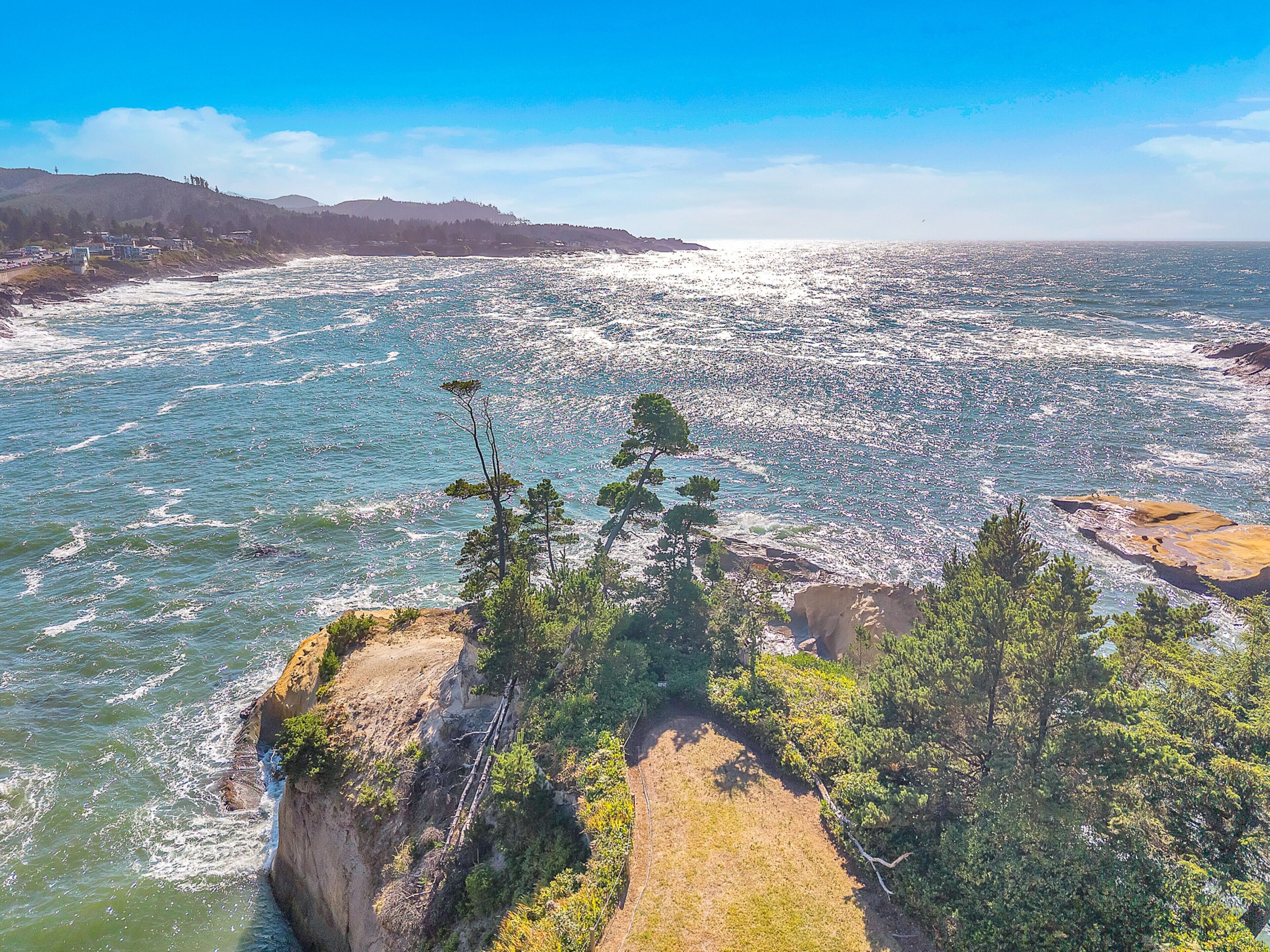 A coastal landscape with rocky cliffs and dense greenery.