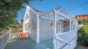 Une terrasse en bois avec des chaises et une pergola.