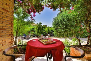 An outdoor patio with a table set for dining, surrounded by greenery and a clear sky. - Agriturismo Al Lago Verde (Alia)