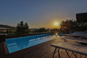 A swimming pool with a wooden deck, lounge chairs, and a view of the sunset. - Agriturismo Al Lago Verde (Alia)