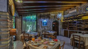A rustic dining area with stone walls, wooden beams, and a variety of food and drink options. - Agriturismo Al Lago Verde (Alia)