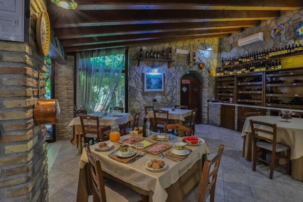 A rustic dining area with stone walls, wooden beams, and a variety of food and drink options. - Agriturismo Al Lago Verde (Alia)
