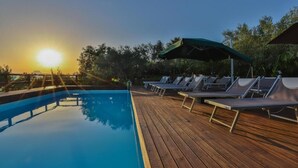 A wooden deck with lounge chairs and a pool at sunset. - Agriturismo Al Lago Verde (Alia)