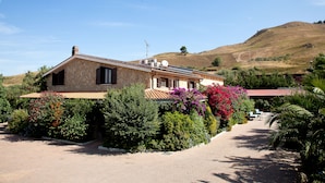 A stone house with a tiled roof, surrounded by lush greenery and flowering plants. - Agriturismo Al Lago Verde (Alia)