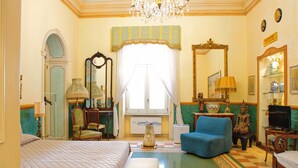 A well-appointed room with a bed, a blue armchair, a television, and a large mirror. - B&B Flora House (Salerno)