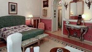 A bedroom with a large bed, a chandelier, a vanity with a mirror, and a small round table. - B&B Flora House (Salerno)