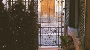 A covered entrance with a wrought iron gate, a tiled pathway, and a potted plant with flowers. - B&B Flora House (Salerno)