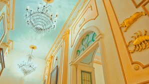 An ornate interior with chandeliers, gold accents, and a green-tinted window. - B&B Flora House (Salerno)