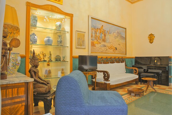A room with a bed, a television, a statue, and a glass display cabinet with decorative items. - B&B Flora House (Salerno)