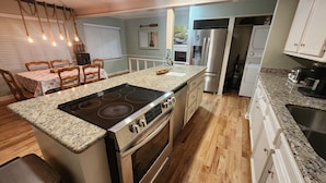 A kitchen with a central island, built-in oven, stainless steel appliances, and a dining area with a table and chairs.