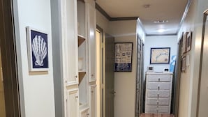 A hallway with wooden flooring, white walls, and doors leading to rooms.