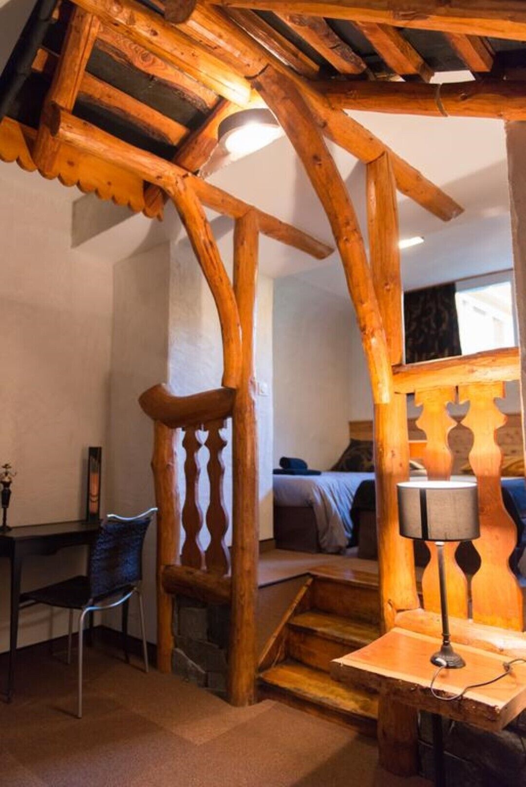 A rustic wooden interior with a bed, a desk, and a chair.