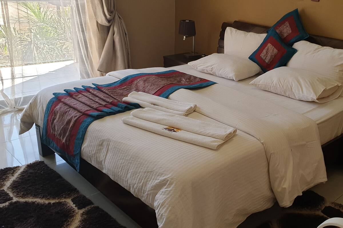 A neatly made bed with a beige bedspread, two pillows, and a decorative throw.