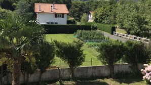 Ein Haus mit rotem Ziegeldach, umgeben von einem gepflegten Rasen und einem weißen Zaun.