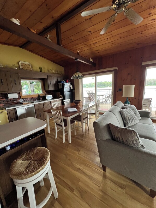A wooden interior with a dining area, kitchen, and a sofa.