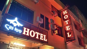 Ein Hotel mit auffälligem Neonlicht, Klimaanlagen und einem Balkon.