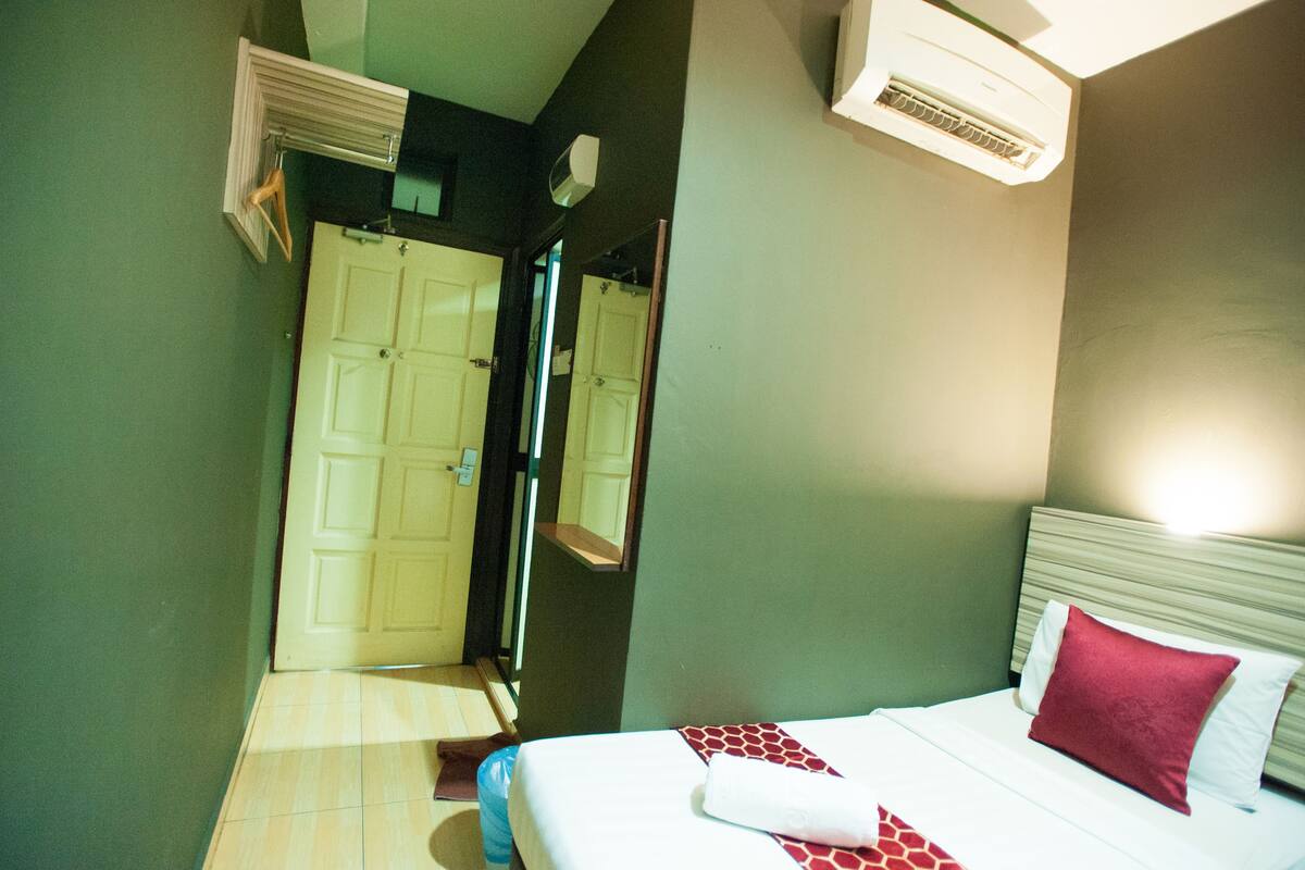 Habitació d'hotel amb un llit, un mirall, un aire condicionat i una porta.