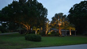 A residential area with a house, palm trees, and a well-maintained lawn.