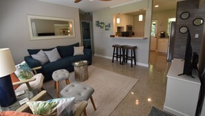 A modern living room with a sofa, armchairs, a coffee table, and a ceiling fan.