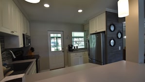 A modern kitchen with white cabinets, stainless steel appliances, and a large island.