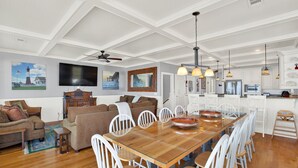Un salón amplio con una mesa de comedor de madera, sillas blancas y un ventilador de techo.